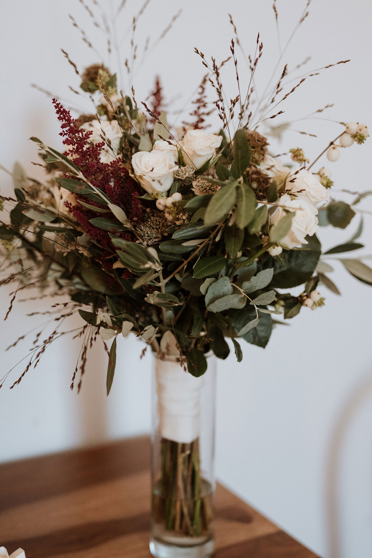 Bouquet da sposa rustico Boho con rose bianche, astilbe rosso bordeaux, graminacee ornamentali ed eucalipto